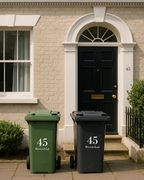Two trash bins, one green and one black, with the number 45 on a house door background.
