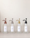 Four glass bottles with metal pumps on a light background