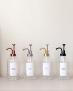 Four glass bottles with metal pumps on a light background